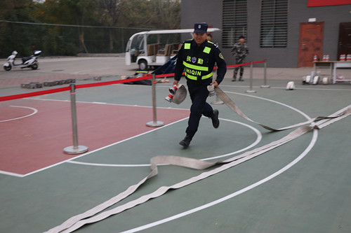 保安员在水带接力项目中手提水带奋力奔跑